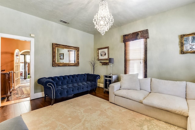 living area featuring arched walkways, a chandelier, visible vents, baseboards, and wood-type flooring