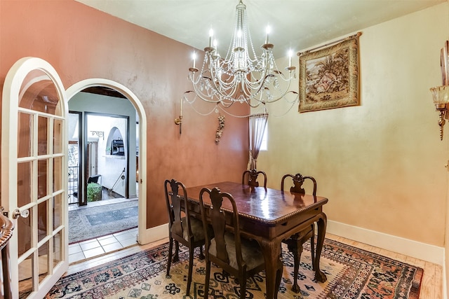 dining area featuring arched walkways, a notable chandelier, and baseboards