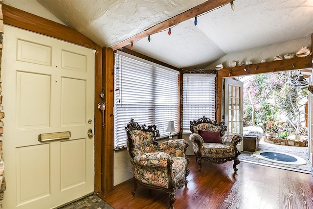 living area featuring lofted ceiling, a textured ceiling, and wood finished floors