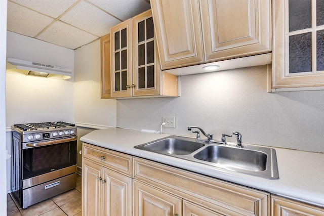 kitchen featuring light countertops, light brown cabinetry, a sink, stainless steel gas range oven, and exhaust hood