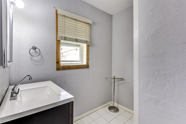 bathroom with tile patterned flooring, a textured wall, vanity, and baseboards