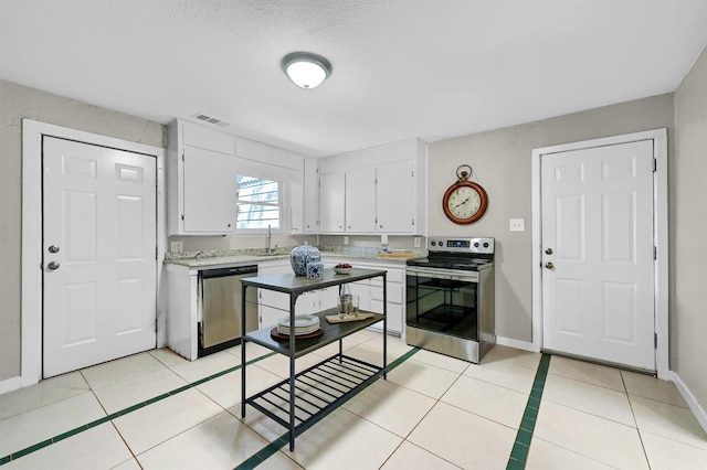 kitchen featuring light tile patterned floors, a sink, visible vents, white cabinets, and appliances with stainless steel finishes