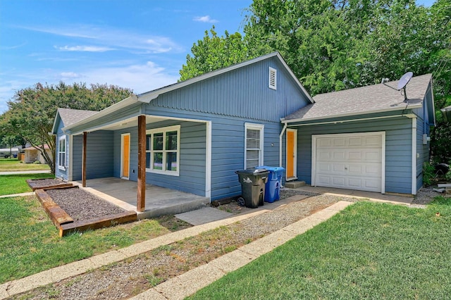 view of side of property with a garage, roof with shingles, a lawn, and covered porch