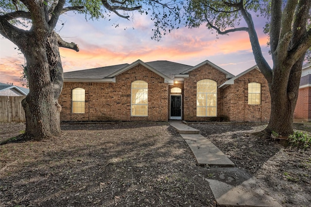 ranch-style house featuring brick siding and fence