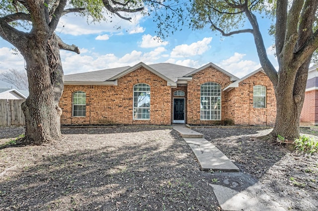 ranch-style house featuring brick siding and fence