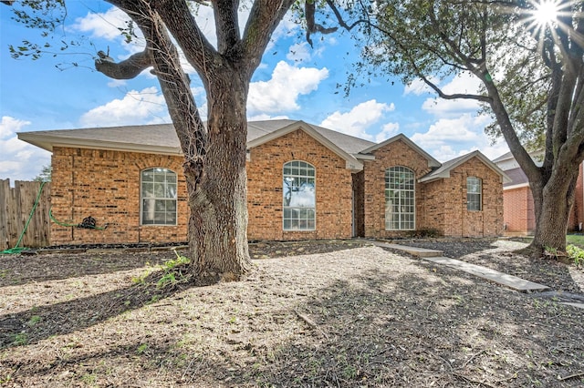 ranch-style house featuring brick siding and fence