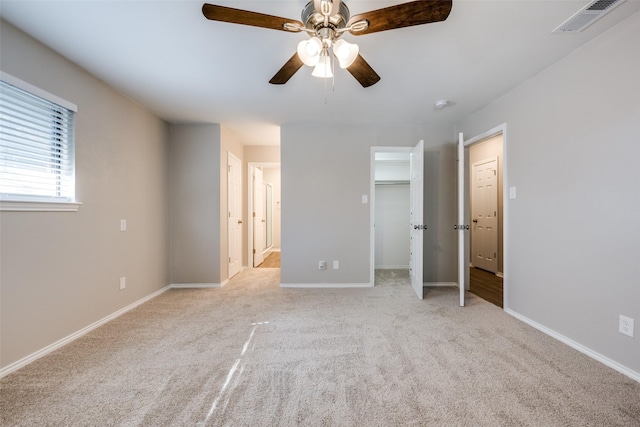 unfurnished bedroom with ceiling fan, connected bathroom, light colored carpet, visible vents, and baseboards