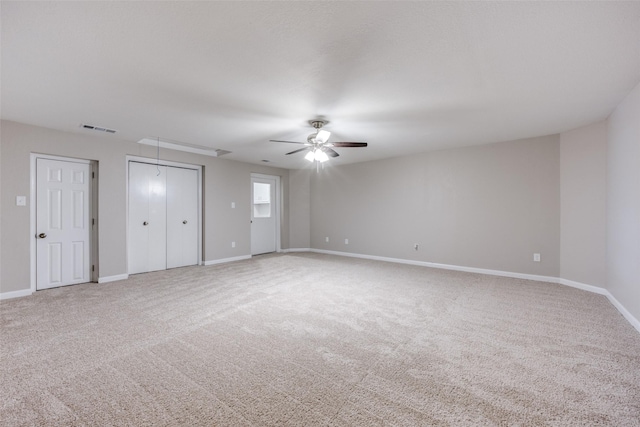 unfurnished bedroom with attic access, visible vents, baseboards, a ceiling fan, and carpet