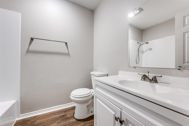 bathroom featuring baseboards, toilet, wood finished floors, walk in shower, and vanity