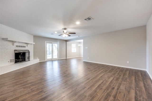 unfurnished living room with a fireplace, dark wood finished floors, and visible vents