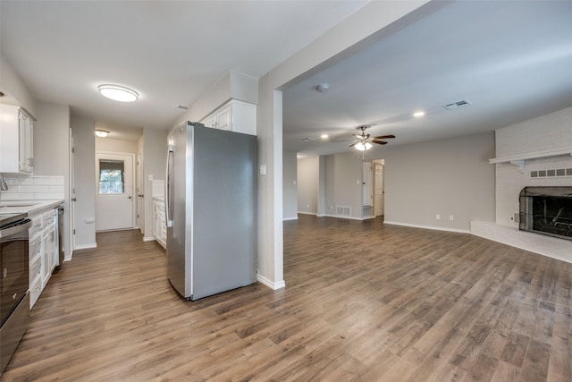 kitchen featuring visible vents, white cabinets, wood finished floors, stainless steel appliances, and a fireplace