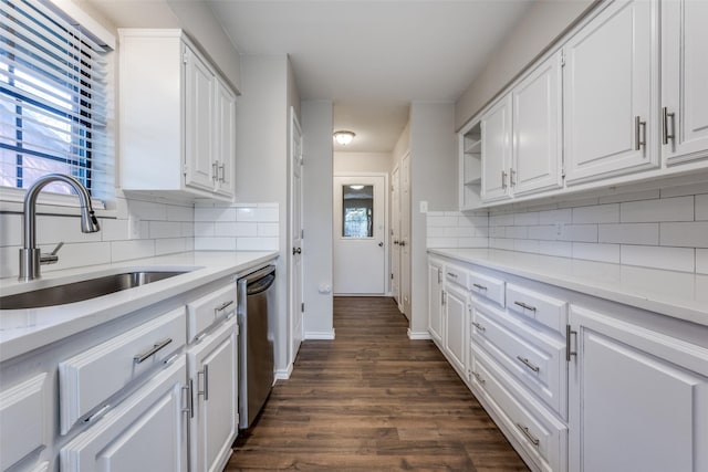 kitchen featuring dark wood-style flooring, tasteful backsplash, stainless steel dishwasher, white cabinetry, and a sink