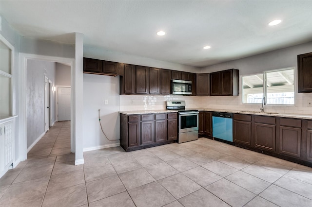 kitchen featuring light tile patterned floors, stainless steel appliances, decorative backsplash, dark brown cabinetry, and a sink