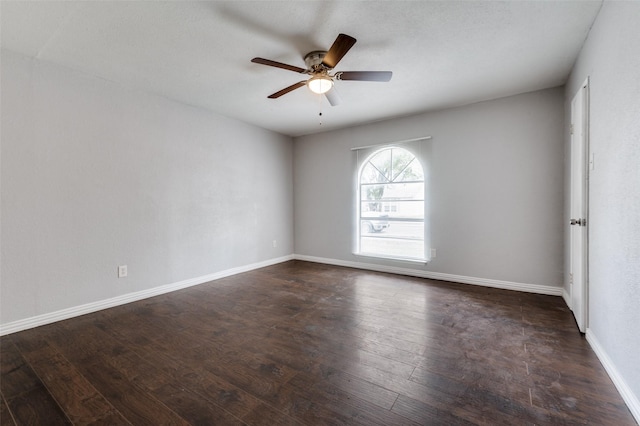 unfurnished room featuring dark wood finished floors, a ceiling fan, and baseboards