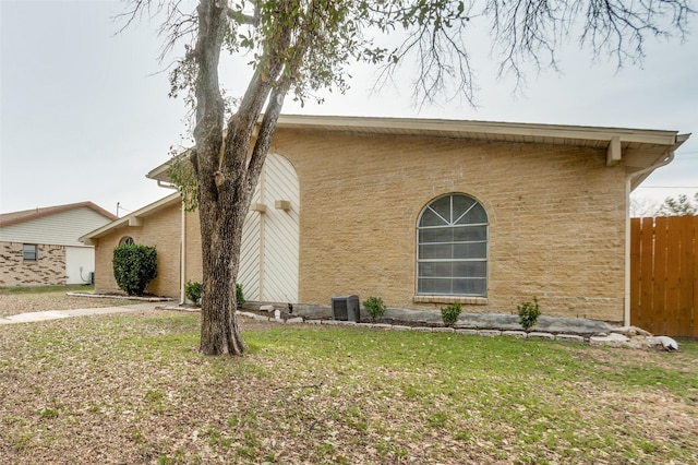 view of side of home with a lawn, fence, and central air condition unit