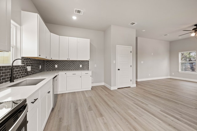 kitchen with dishwasher, backsplash, a sink, and visible vents