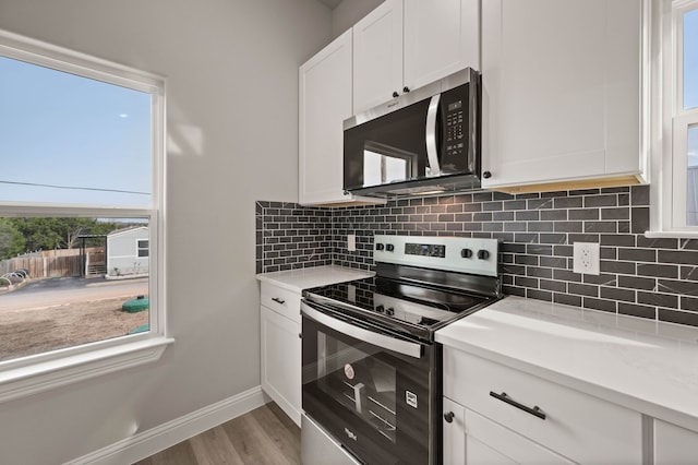 kitchen featuring stainless steel appliances, light countertops, decorative backsplash, and white cabinetry