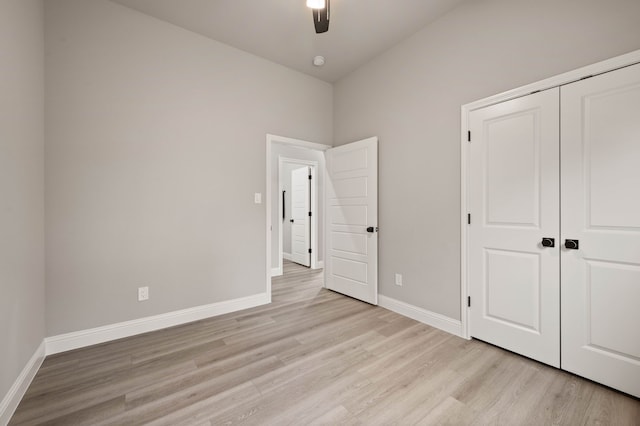 unfurnished bedroom with light wood-style floors, a closet, ceiling fan, and baseboards