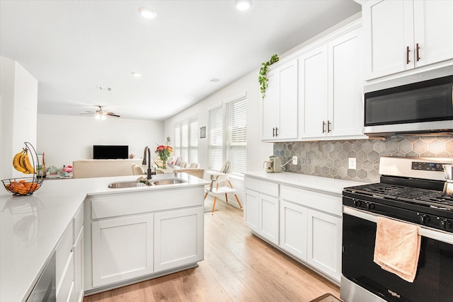 kitchen with light wood-style floors, appliances with stainless steel finishes, light countertops, and a sink