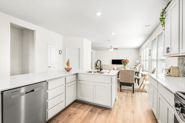 kitchen featuring appliances with stainless steel finishes, light countertops, a sink, and light wood-style flooring