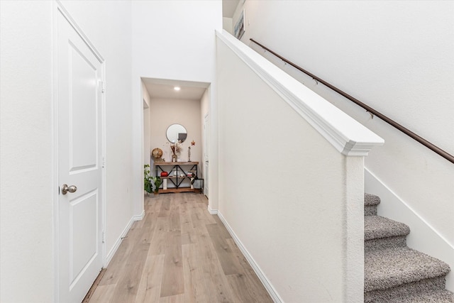 hall with stairs, light wood finished floors, and baseboards