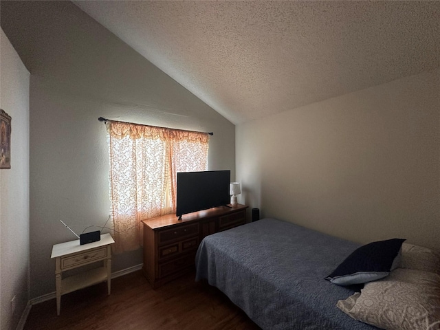 bedroom with vaulted ceiling, a textured ceiling, and dark wood finished floors