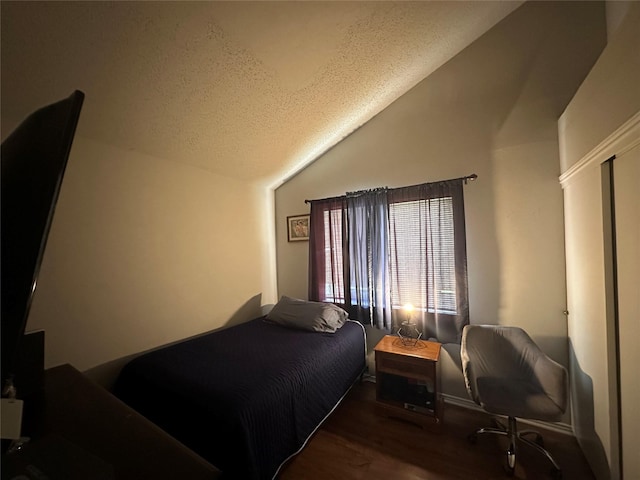 bedroom with vaulted ceiling, a textured ceiling, and wood finished floors