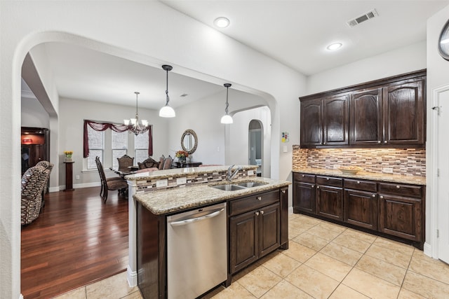 kitchen with visible vents, backsplash, dishwasher, arched walkways, and a sink