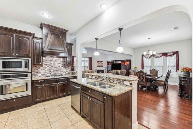 kitchen with visible vents, custom exhaust hood, a sink, appliances with stainless steel finishes, and tasteful backsplash