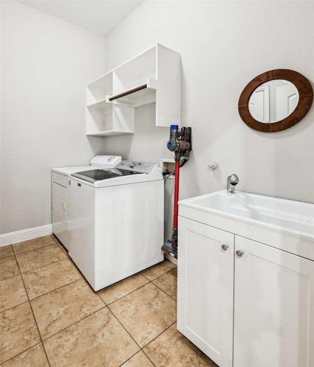 laundry room with washer and clothes dryer, a sink, cabinet space, light tile patterned floors, and baseboards