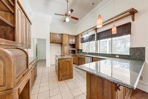 kitchen with light tile patterned floors, a peninsula, open shelves, brown cabinetry, and crown molding