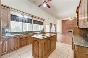 kitchen featuring ornamental molding, brown cabinets, a center island, a sink, and light tile patterned flooring