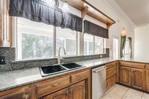 kitchen with light tile patterned floors, brown cabinetry, dishwasher, backsplash, and a sink