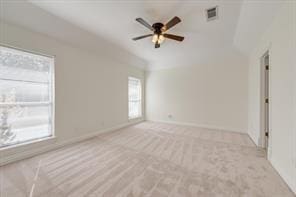 spare room with ceiling fan, light carpet, visible vents, baseboards, and vaulted ceiling