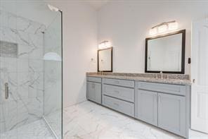 full bath featuring a sink, marble finish floor, double vanity, and a marble finish shower