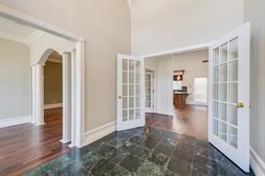 interior space featuring arched walkways, french doors, baseboards, and wood finished floors