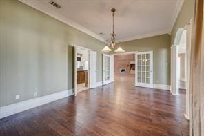 spare room featuring ornamental molding, visible vents, baseboards, and dark wood-style floors