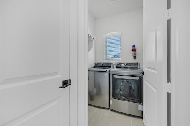 clothes washing area featuring laundry area, washer and dryer, and light tile patterned flooring