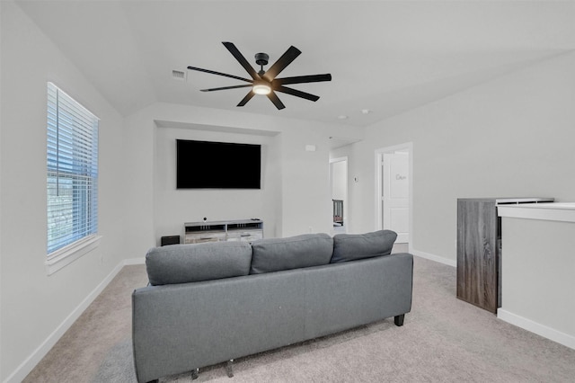 living area featuring lofted ceiling, baseboards, visible vents, and light colored carpet