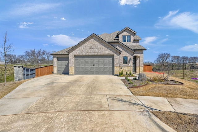 french country inspired facade featuring an attached garage, brick siding, fence, concrete driveway, and roof with shingles