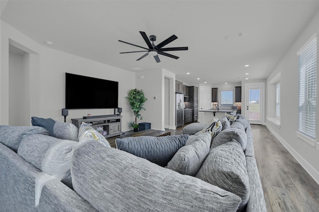 living room with light wood-type flooring, ceiling fan, baseboards, and recessed lighting