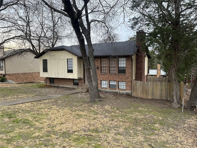 back of house with brick siding, fence, and a chimney