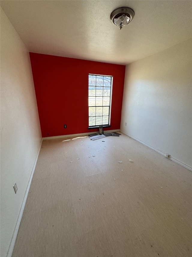 spare room featuring a textured ceiling and baseboards