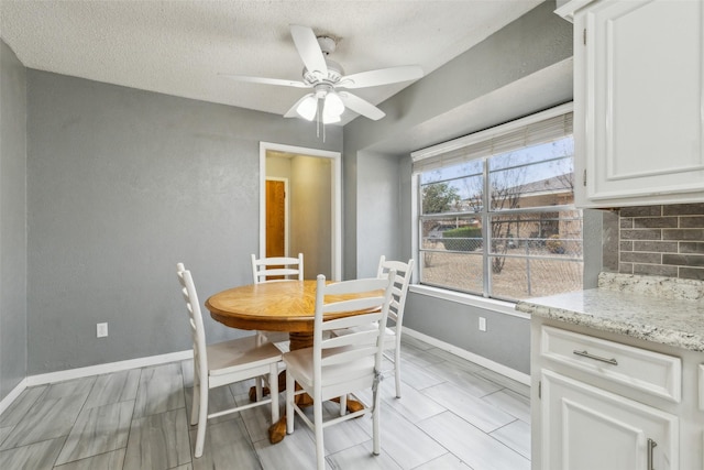 dining room with a textured ceiling, a ceiling fan, and baseboards