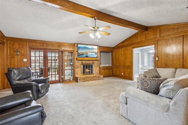 living room featuring wooden walls, light colored carpet, a textured ceiling, french doors, and a brick fireplace