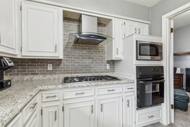 kitchen featuring wall chimney exhaust hood, appliances with stainless steel finishes, decorative backsplash, and white cabinets