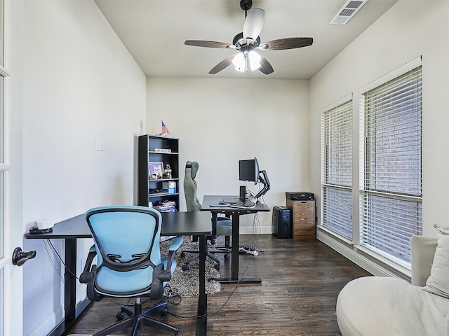 office featuring dark wood-type flooring, visible vents, ceiling fan, and baseboards