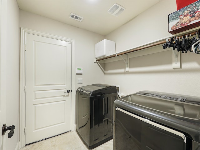 laundry area featuring light tile patterned floors, laundry area, washer and clothes dryer, and visible vents