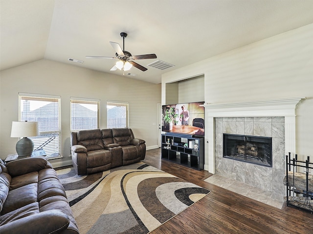 living area featuring a wealth of natural light, a tiled fireplace, wood finished floors, and visible vents