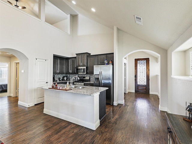 kitchen with visible vents, arched walkways, dark wood-style floors, stainless steel appliances, and a sink